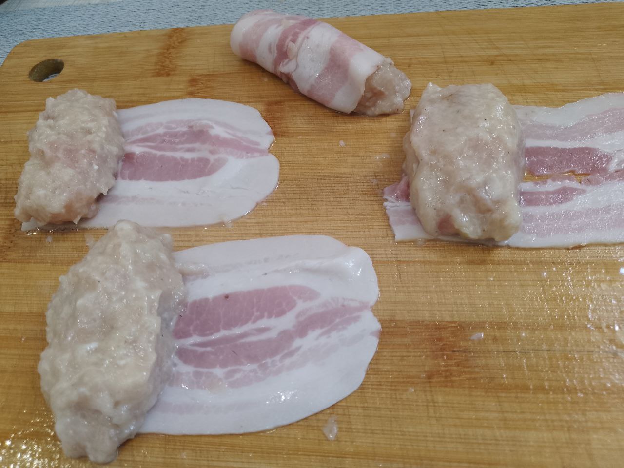 Рулетики из куриного фарша в беконе, в духовке: Фарш разделяем на одинаковые части. На полоску бекона кладем фарш и плотно заворачиваем. Чтобы рулетики были