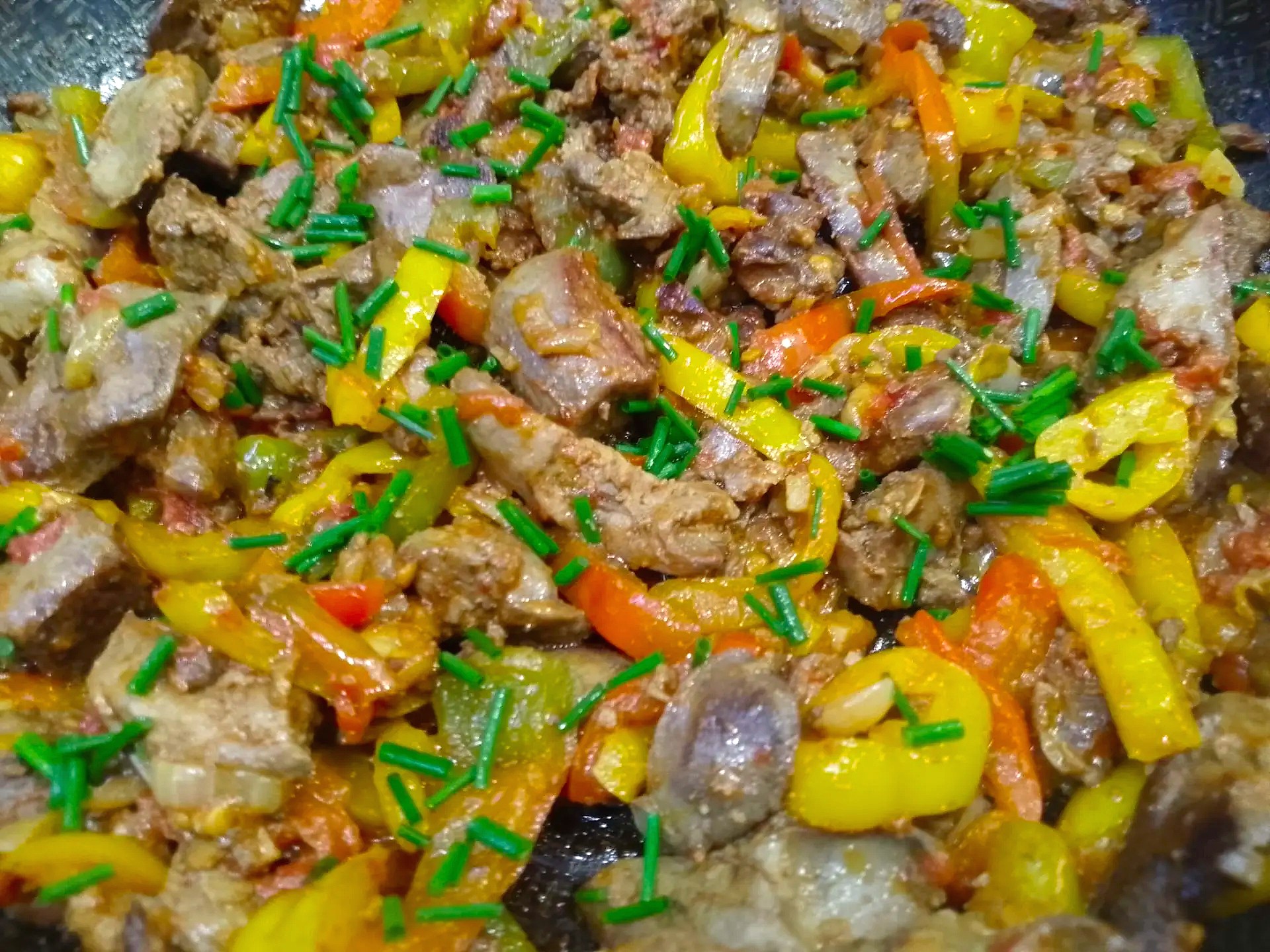 Посыпание готовой жареной печени с овощами зеленым луком